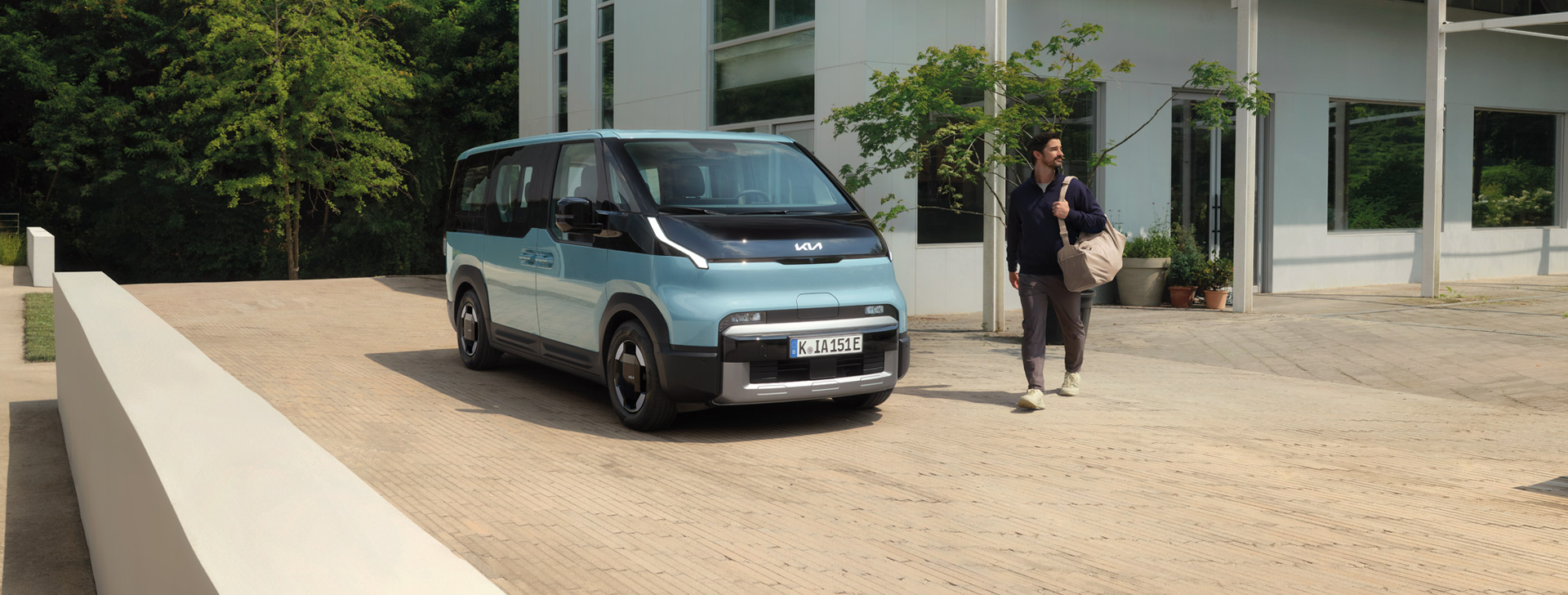 Kia PV5 Passenger vor einem modernen Gebäude in Vorderansicht mit Talent