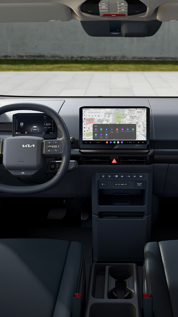 Fahrerbereich des Kia PV5 WAV mit Lenkrad, digitalem Kombiinstrument, zentralem Display und Cockpit-Layout
